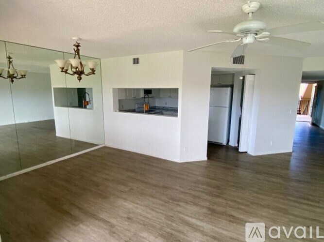A spacious room with a wooden floor and a ceiling fan.