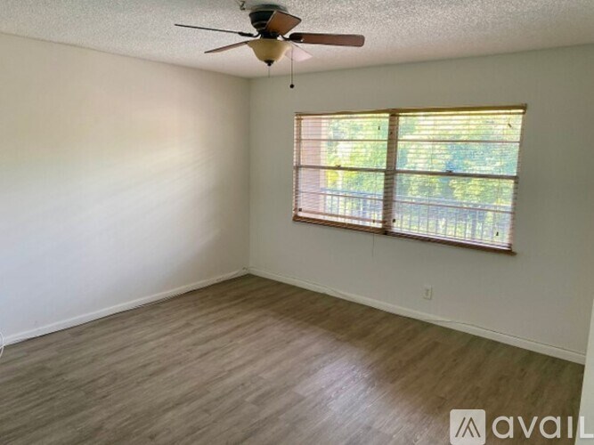 A room with a ceiling fan and a window with blinds.