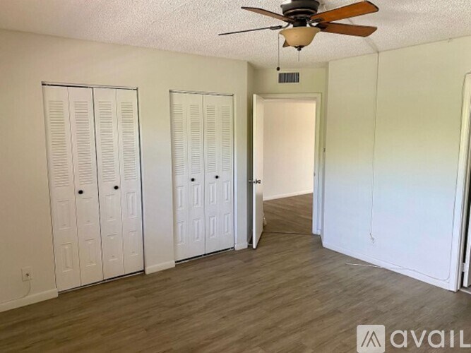 A room with a ceiling fan and three white closets.