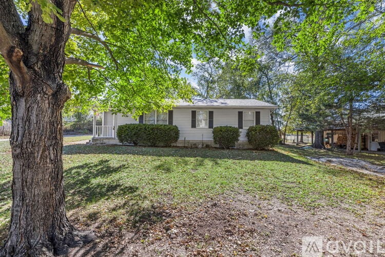 A house is surrounded by a green lawn and trees.