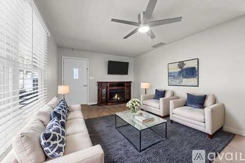 A living room with a white couch, a glass coffee table, and a television mounted on the wall.