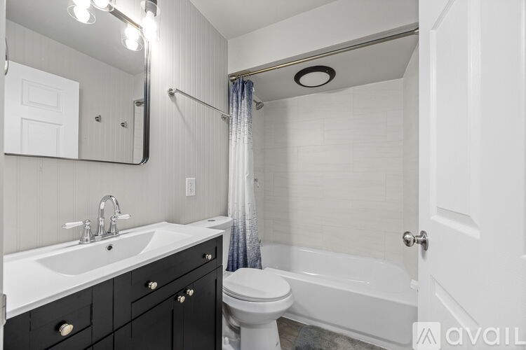 A bathroom with a white sink, black drawers, a white toilet, and a white bathtub.