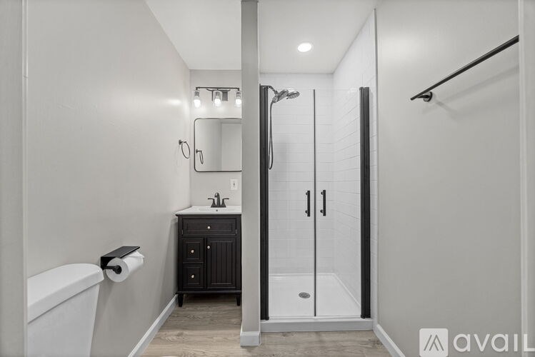A bathroom with a white tub, a sink, a mirror, and a walk-in shower.