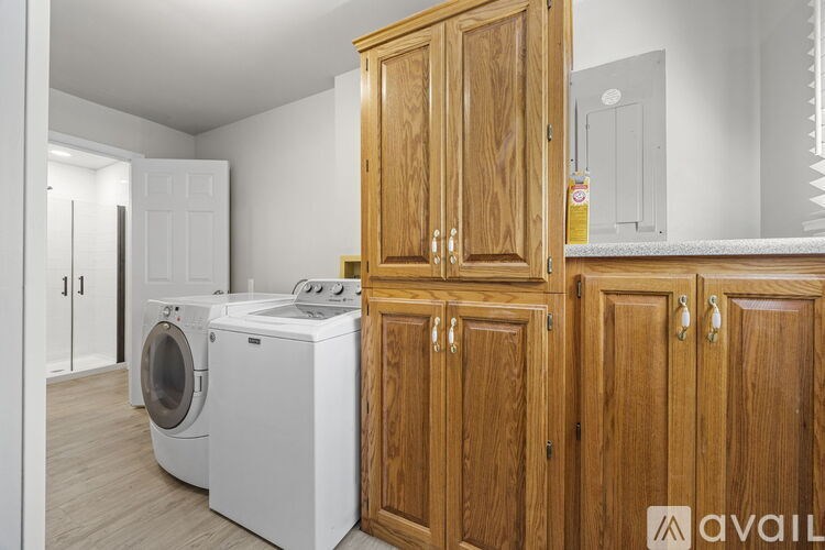 A laundry room with a washer and dryer and wooden cabinets.