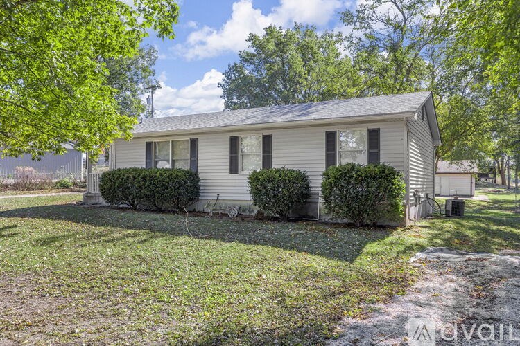 A house with a lawn and trees in the background.