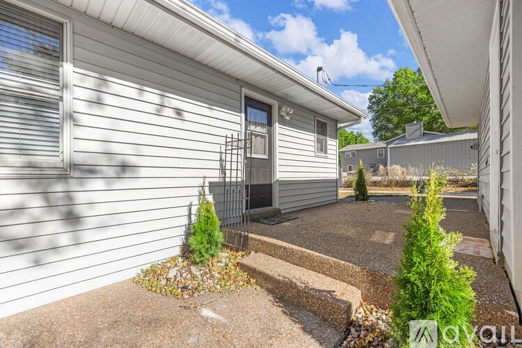 A small house with a grey siding and a small garden in front.