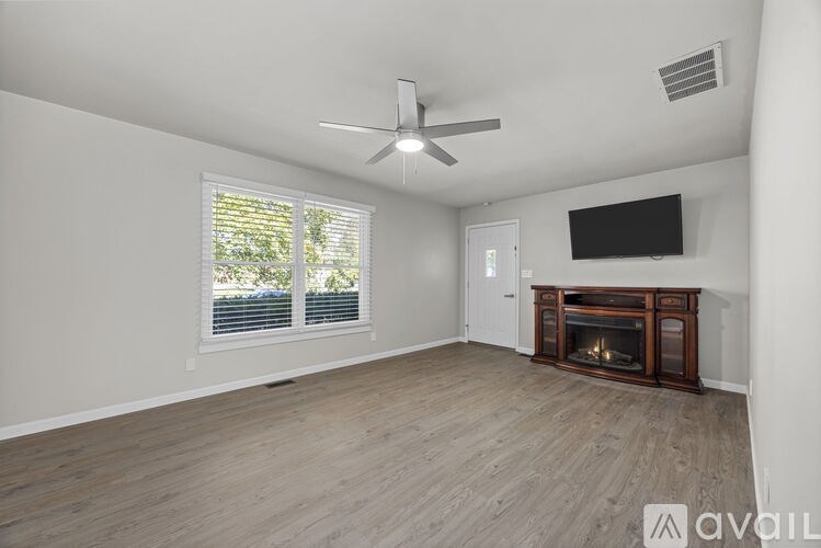 A living room with a fireplace and a flat screen TV mounted on the wall.