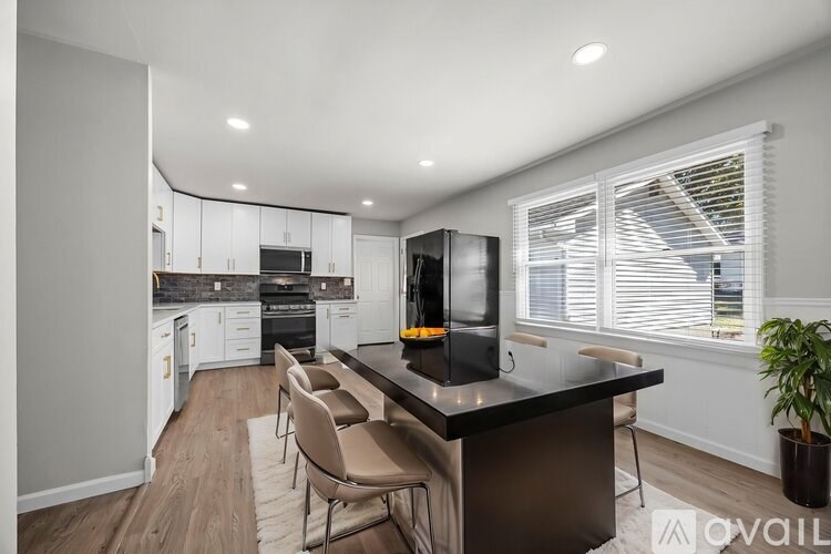 A modern kitchen with a black countertop and stainless steel appliances.
