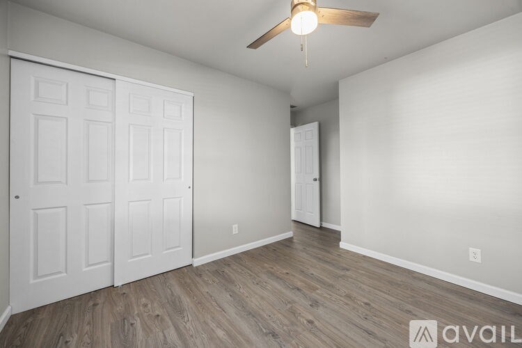 A room with a ceiling fan and two doors.
