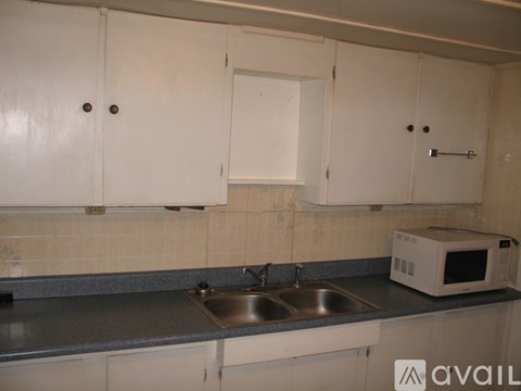 A kitchen with white cabinets and a microwave on the counter.
