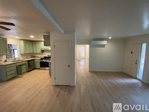 A spacious kitchen with green cabinets and a white door.
