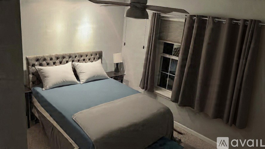 A bed with a blue sheet and a grey headboard is in the image.