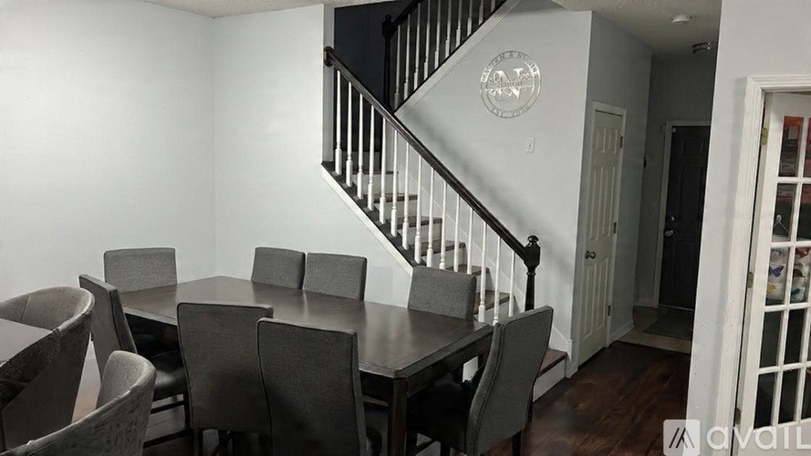 A dining room with a table and chairs and a staircase.