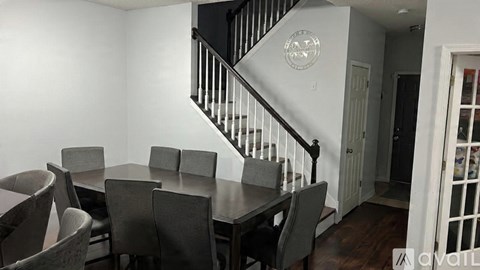 A dining room with a table and chairs and a staircase.
