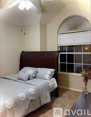 A bedroom with a bed, a table, and a window.