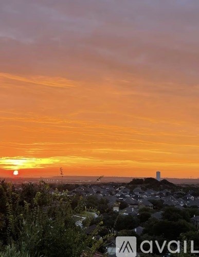 A sunset view with a town in the foreground and a tower in the distance.