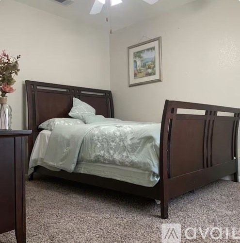 A bed with a wooden headboard and a grey bedspread is in the image.