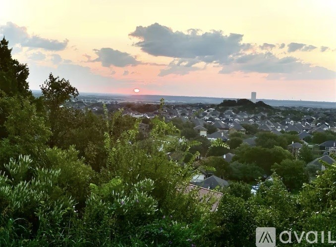 A sunset view of a town with a tower in the distance.