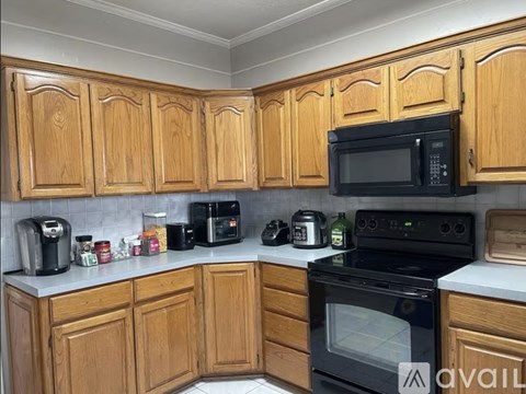 A kitchen with wooden cabinets and a black microwave above the oven.