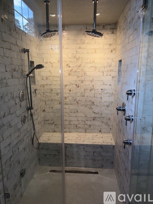 A bathroom with a white brick wall and a glass shower door.