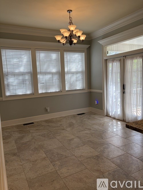 A room with a chandelier, tiled floor, and a window with blinds.