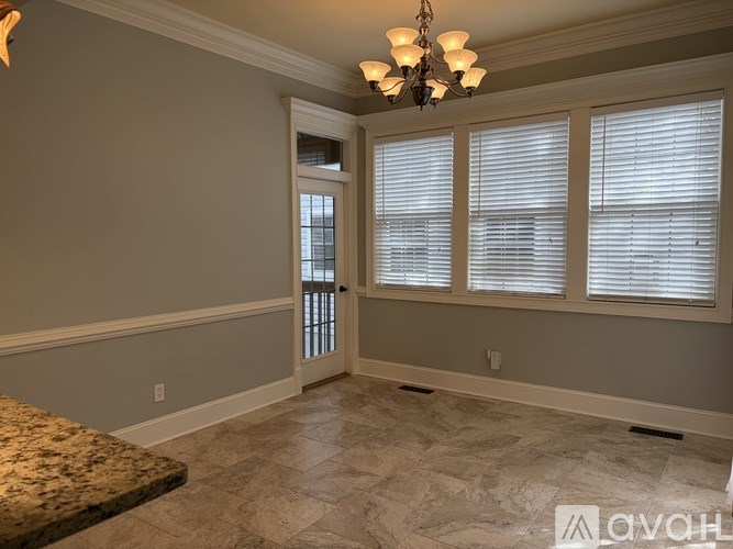 A room with a chandelier, a marble floor, and a door leading to a balcony.