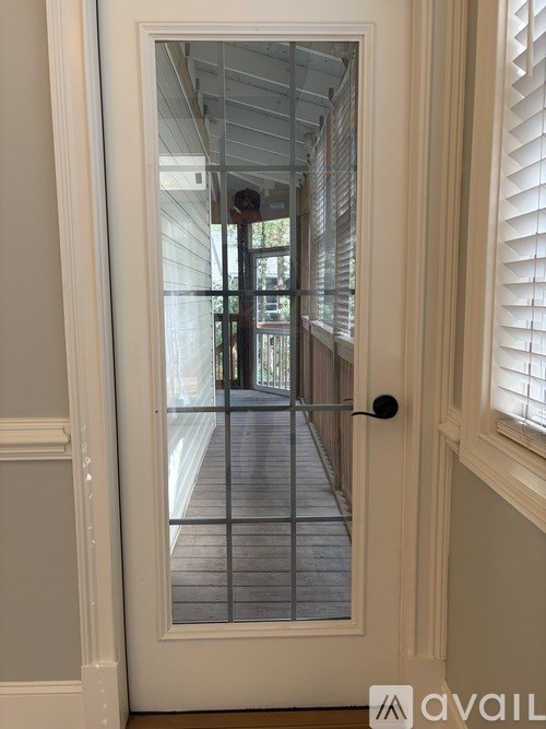 A door with a glass window showing a hallway with a metal railing.