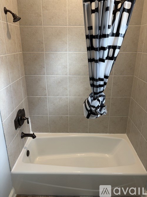 A white bathtub with a black and white striped shower curtain.