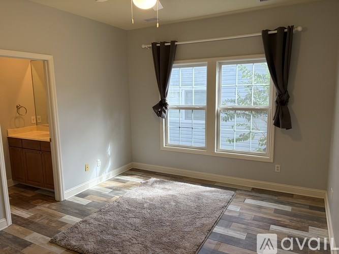 A room with a large window and a rug on the floor.