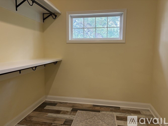A room with a window and a rug on the floor.