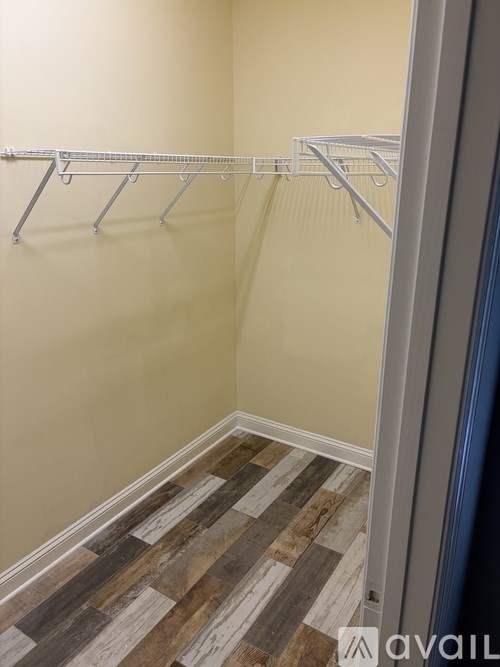 A room with a wooden floor and a white wall with a metal rack on it.