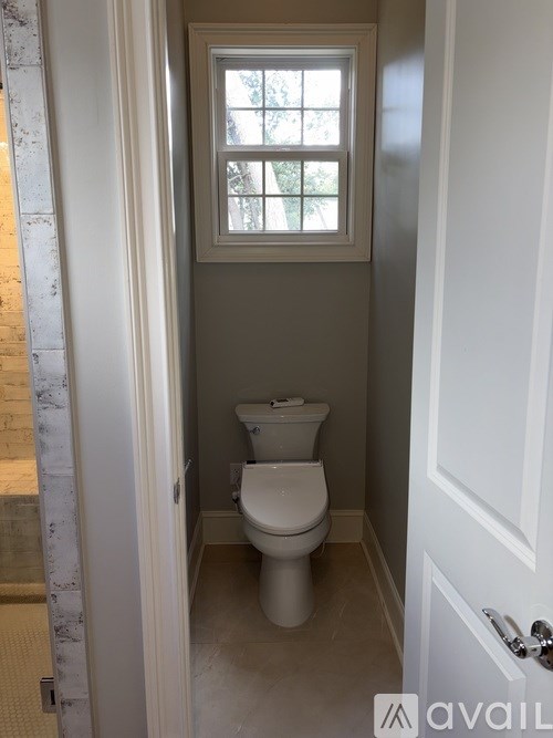 A bathroom with a toilet and a window.