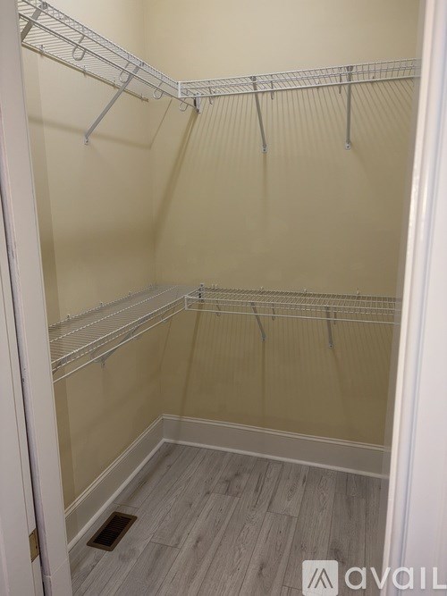 A walk-in closet with white shelving and a wooden floor.