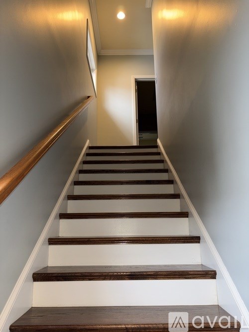 A staircase with wooden steps and a white wall.