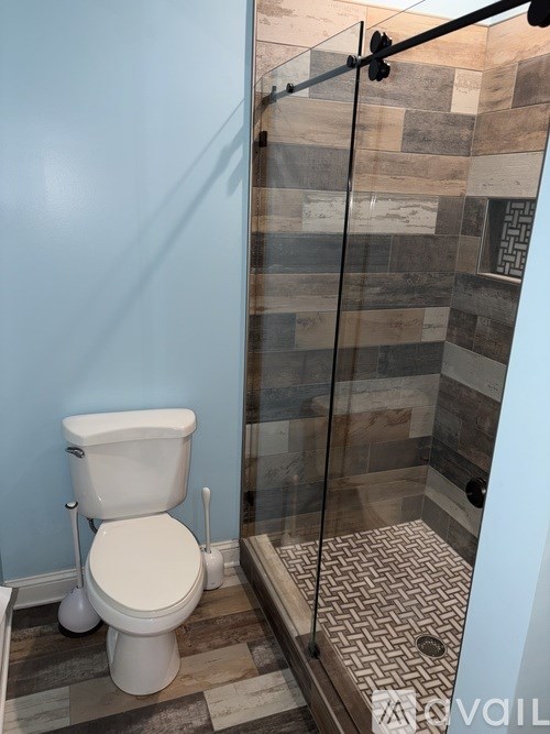 A white toilet with a glass shower door in a bathroom.