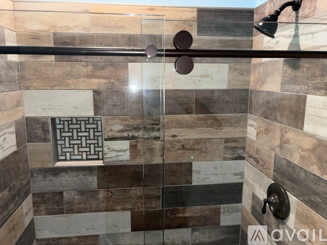 A shower with a glass door and a tiled wall.