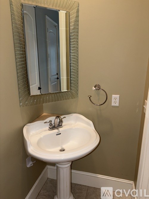 A white pedestal sink with a silver faucet and a mirror above it.