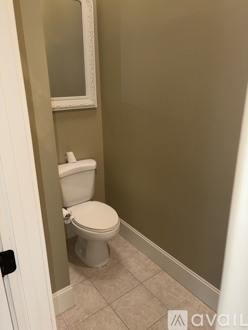 A white toilet in a bathroom with a white door and a mirror.
