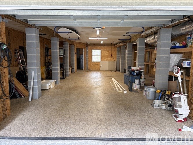 A spacious garage with a concrete floor and various tools and equipment scattered throughout.