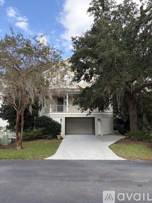 A house with a driveway and a tree in front of it.