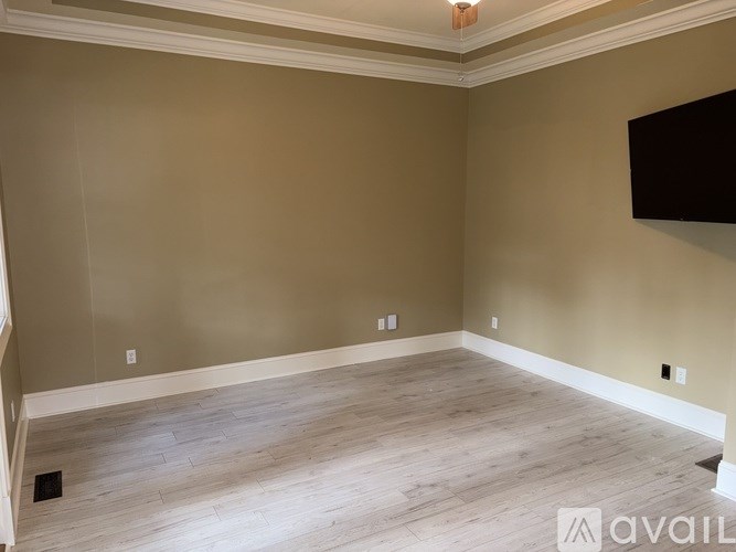 A room with beige walls and wooden flooring is available for rent or purchase.