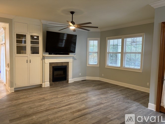 A living room with a fireplace and a television mounted above it.