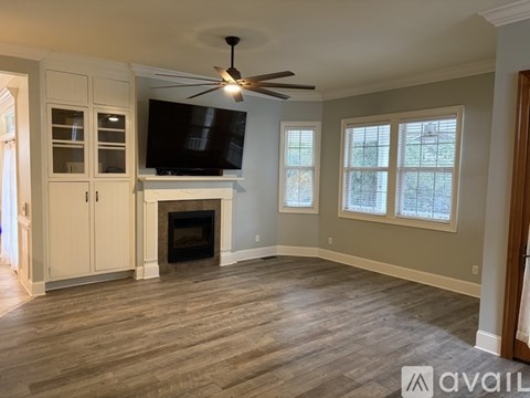 A living room with a fireplace and a television mounted above it.
