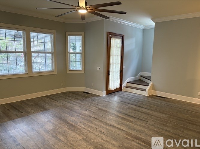 A room with a ceiling fan and wooden flooring.