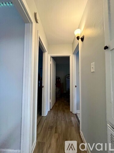 A long hallway with white walls and wood flooring.