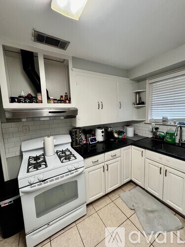 A kitchen with white cabinets and a black countertop.