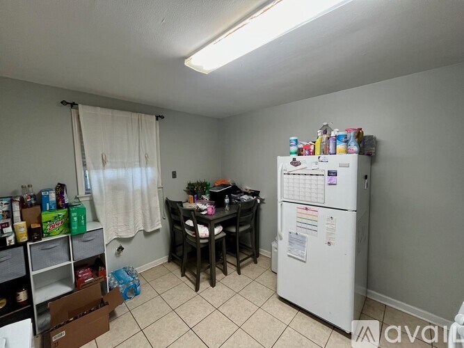 A kitchen with a white fridge, a table with chairs, and a pantry with shelves.