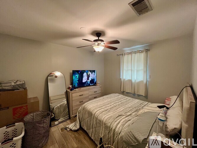 A bedroom with a bed, dresser, and a ceiling fan.