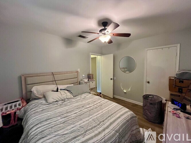 A bedroom with a bed, dresser, mirror, and a ceiling fan.