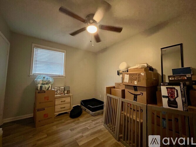 A room with a ceiling fan and boxes on the floor.
